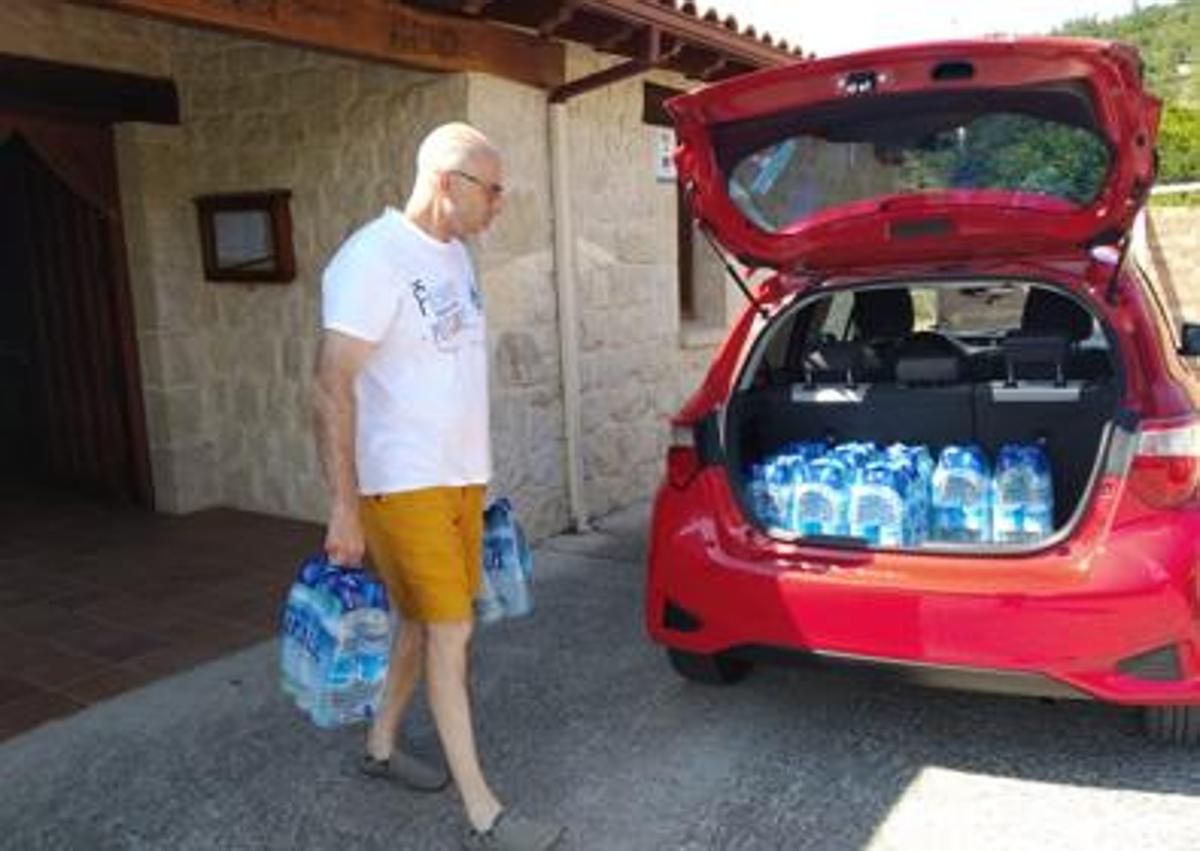 Imagen secundaria 1 - Dos vecinos recogían agua embotellada de la Casa del Concejo cuando no podían consumir la del grifo. 